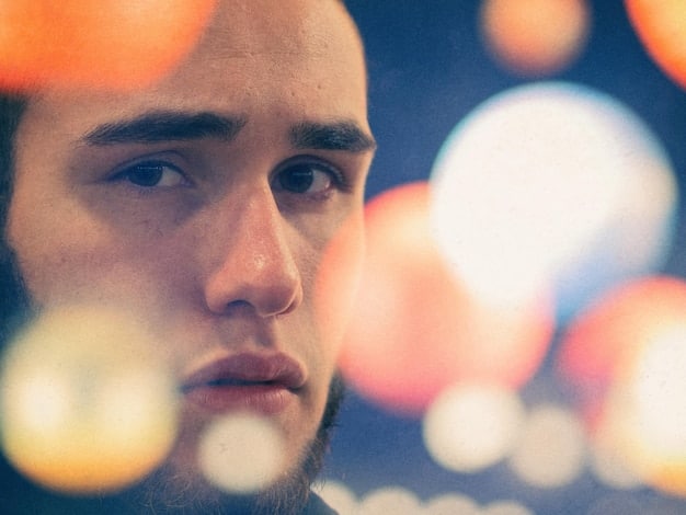 A close-up shot of a person's face expressing a mix of sadness and determination. The background is blurred to focus on the individual's emotional state.