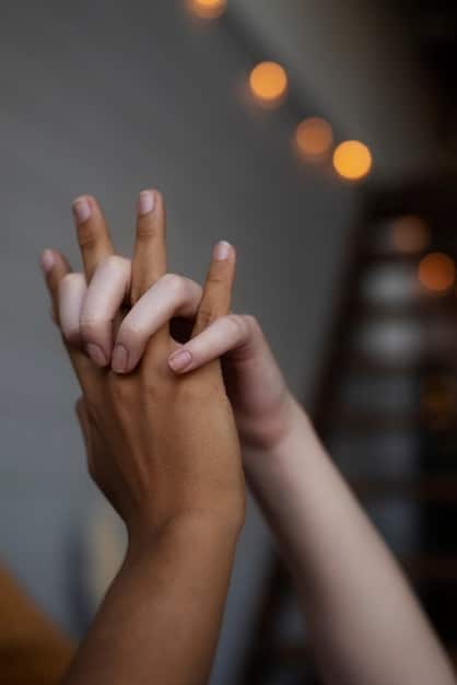 A close-up shot of two hands intertwined, symbolizing connection and support. The background is softly blurred, focusing attention on the hands.