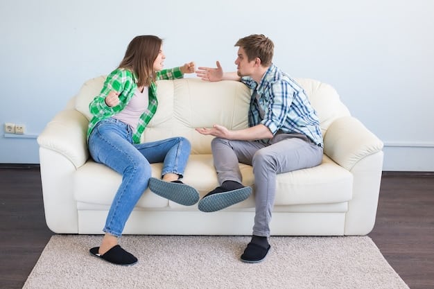 A couple sits on a sofa, facing each other, with one partner actively listening and nodding while the other speaks, signifying attentive communication.