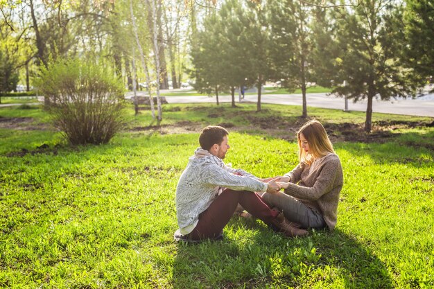 A couple is sitting outdoors in a park, having a heartfelt conversation, with sunlight filtering through the trees.