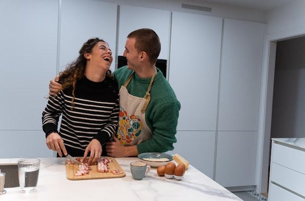 A couple laughing and playfully touching each other in the kitchen while cooking together, symbolizing shared activities and joyful moments.