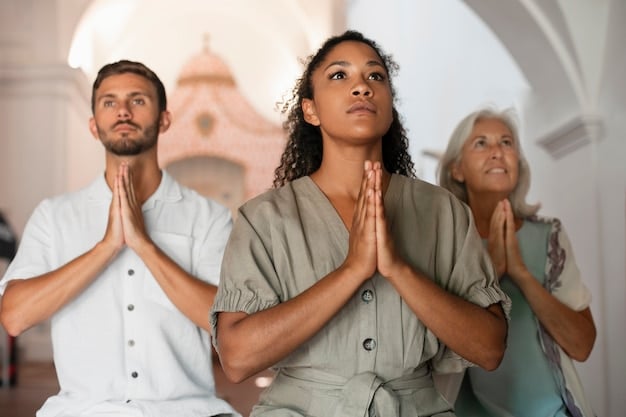 A close-up shot of a diverse group of people meditating together in a sunlit studio. They are sitting comfortably on cushions, eyes closed, with serene expressions. Soft, natural light fills the room, enhancing the peaceful atmosphere.