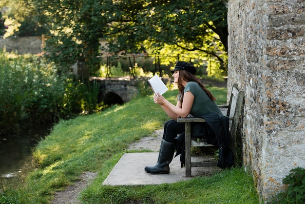 A person journaling outdoors in a peaceful garden setting. They are sitting on a bench, with a notebook and pen in hand, looking thoughtful and reflective. The garden is filled with colorful flowers and lush greenery, creating a serene and inspiring atmosphere.