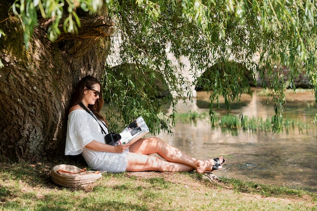 A person sitting on a park bench, surrounded by trees, deeply engaged in reading a book, showcasing a peaceful and relaxing outdoor activity.