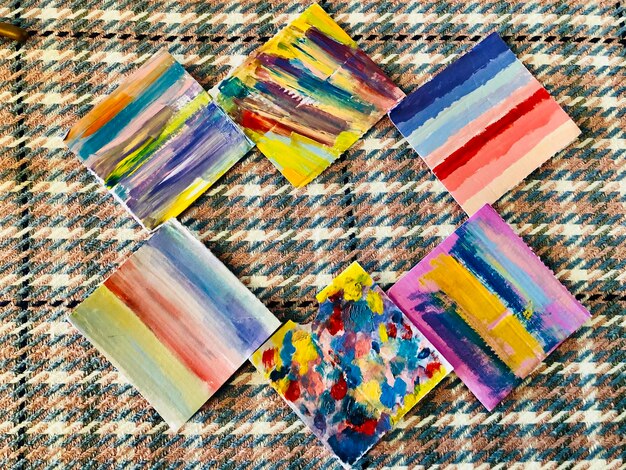 A collection of colorful hand-painted canvases, each displaying different abstract patterns and textures.