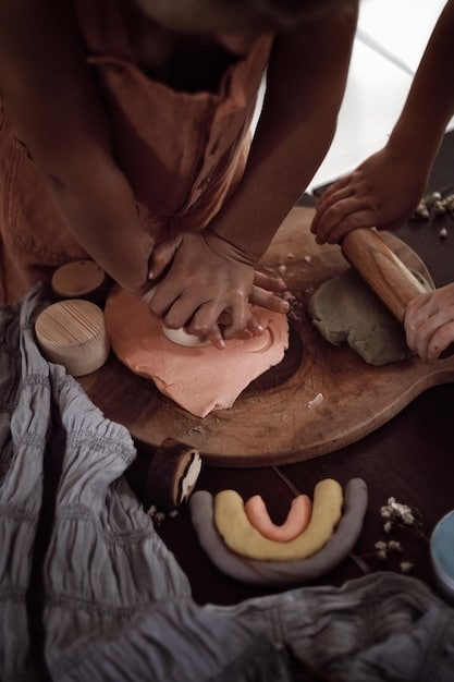 A close-up of hands sculpting clay, with various sculpting tools and finished pottery pieces in the background.