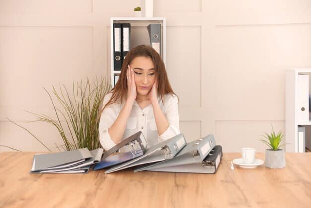 A person sitting at a desk, looking stressed with hands on their head, paperwork scattered around, indicating workplace stress.