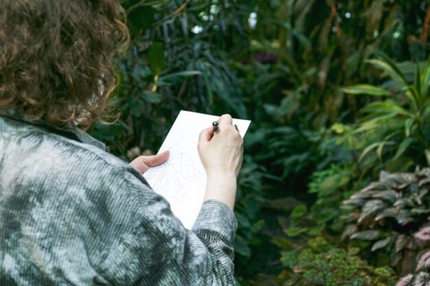 A close-up of a hand holding a pen and writing in a journal, with blurred background of green plants, suggesting a connection to nature and mindfulness.