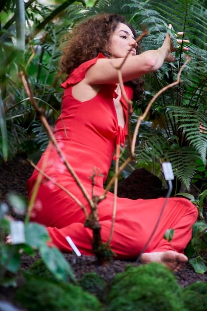 A serene woman meditating outdoors, surrounded by lush greenery, representing the concept of finding peace and tranquility through self-care practices.