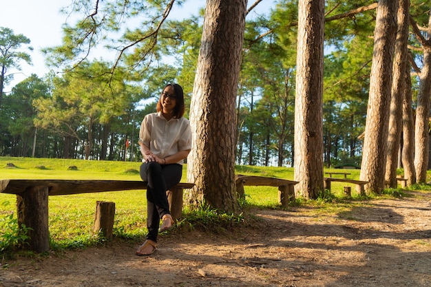 A person sitting on a park bench, eyes closed, smiling slightly, with sunlight filtering through the trees, representing the integration of mindfulness into everyday life.