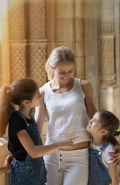 A close-up shot of a female teacher leading a small group of middle school students in a breathing exercise. The students are sitting comfortably, hands resting on their laps, eyes gently closed, with an expression of calm concentration on their faces. The teacher is smiling encouragingly.
