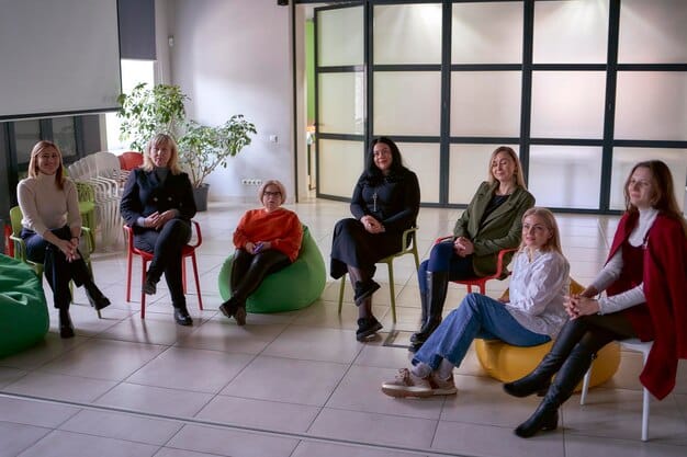 A group of teachers participating in a mindfulness training workshop. They are sitting on cushions in a circle, led by a mindfulness expert, practicing mindful listening. The atmosphere is supportive and engaged, with teachers actively participating and sharing their experiences.