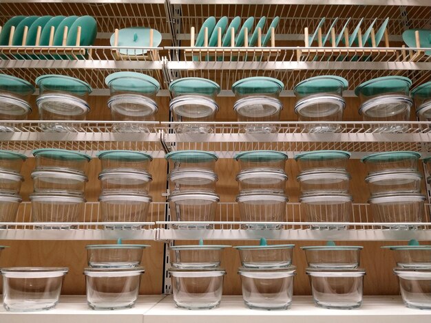 Rows of clear glass containers filled with pre-portioned meals are neatly arranged on a refrigerator shelf. Each container holds a balanced combination of cooked grains, grilled chicken or tofu, and colorful roasted vegetables, showcasing a well-organized and healthy meal prep.
