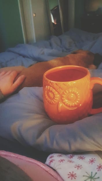 A bedside table with a cup of herbal tea, a book, and a sleep mask, illustrating a calming bedtime routine that promotes relaxation and prepares the body for sleep.