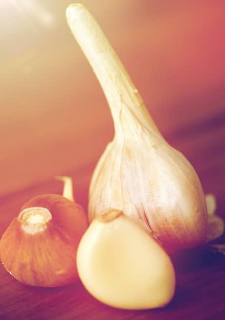 A close-up shot of garlic cloves being peeled, alongside a piece of fresh ginger root. The background showcases various healthy food ingredients, emphasizing a holistic approach to immune system boosting.