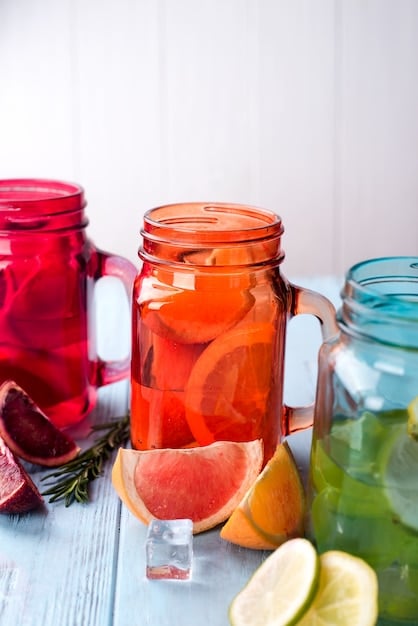 Several colorful glass pitchers filled with different variations of infused water, including lemon-lime, strawberry-basil, and cucumber-mint. The pitchers are arranged on a wooden table with sunlight streaming in.