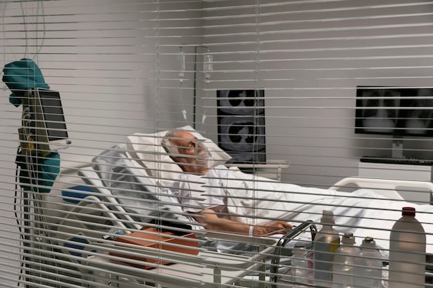 A patient lying comfortably in a medical bed, receiving medication intravenously. A nurse is monitoring the patient's vitals and providing support. The setting is a clean, sterile medical environment.