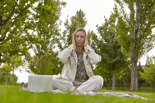 A person practicing mindful meditation outside in nature, seated comfortably on a mat with their eyes closed, surrounded by lush greenery.