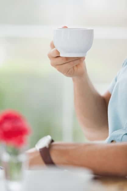 A close-up photo of a person's hands gently holding a teacup, showcasing the mindful practice of paying attention to the senses while engaged in everyday activities.