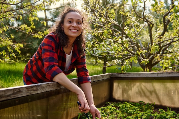 A person smiling while volunteering at a community garden, surrounded by lush greenery. The setting is bright and cheerful, suggesting purpose and positive engagement. This illustrates finding identity and fulfillment outside of traditional employment.