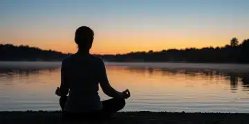 Person meditating by a lake at sunrise, symbolizing emotional balance and serenity