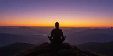 Person meditating on mountain, symbolizing emotional strength and peace.