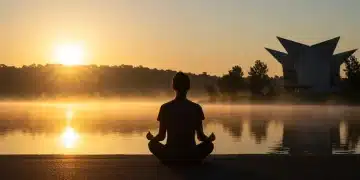 Person meditating by a lake at sunrise, symbolizing long-term sobriety and peace.