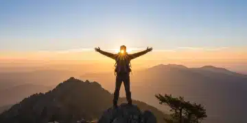 Person on mountain peak at sunrise, symbolizing freedom and new beginnings in sobriety.